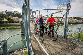 Couple pushes their bike over the Mozartsteg