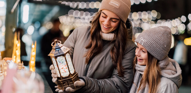 A young woman and a girl happily look at a christmas decoration. | © TSG Tourismus Salzburg GmbH, Skyline Medien